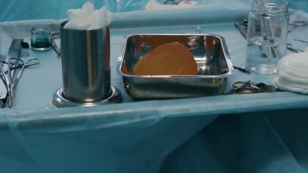 Хирургические инструменты. Хирургические инструменты и разложенные на стерильном столе, подготовленные к операции крупным планом, на фоне команды хирургов абстрактный фон . — стоковое видео
