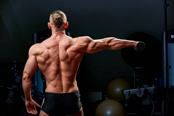 Uomo atletico in posa. Foto di uomo con fisico perfetto su sfondo nero. Vista posteriore. Forza e motivazione — Foto Stock