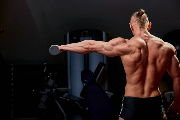 Atletisk man poserar. Foto av mannen med perfekt kroppsbyggnad på svart bakgrund. Bakifrån. Styrka och motivation — Stockfoto