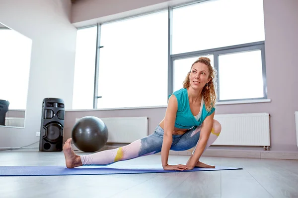 Büyük ilerleme. Spor salonunda pencerenin önünde uzanan yapıyor genç güzel kadın — Stok fotoğraf