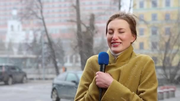 Piękna Blondynka reporterka transmitująca podczas Snowfall. Nowości koncepcyjne, zła pogoda. Dziennikarz emituje na ulicy miasta. — Wideo stockowe