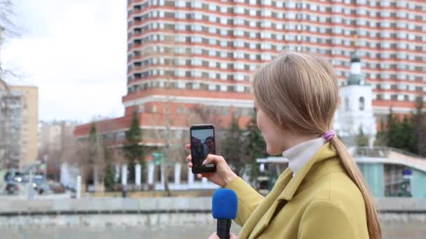 Mooi meisje reporter maakt selfie met een film crew. Concept nieuws. De journalist zendt uit op City Street. Teamwork. — Stockvideo