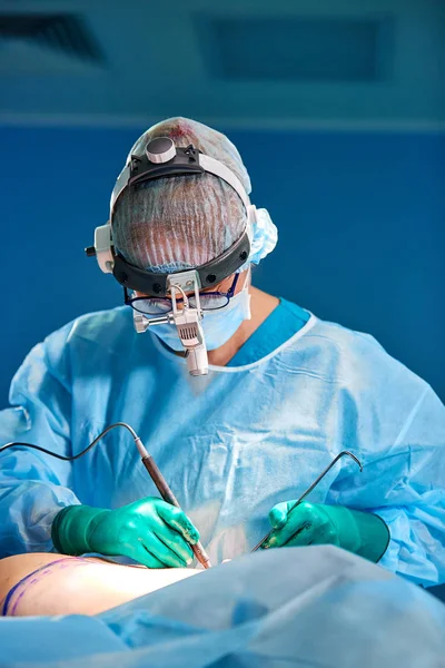 Kozmetikai műtétet végző sebész a kórházi műtőben. Egy maszkos sebész, aki hangokat visel az orvosi prokadúra alatt. Mellnagyobbítás — Stock Fotó
