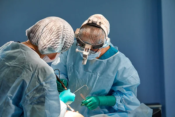 Cerrah hastane ameliyathanesinde estetik ameliyat yapıyor. Tıbbi gelişim sırasında maske takan bir cerrah. Göğüs büyütme. — Stok fotoğraf