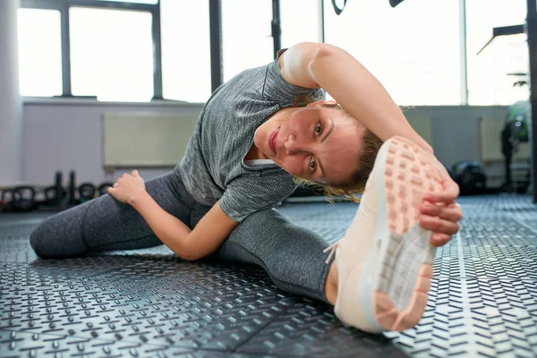 De grands progrès. Jeune belle femme en vêtements de sport faisant étirement devant la fenêtre à la salle de gym — Photo