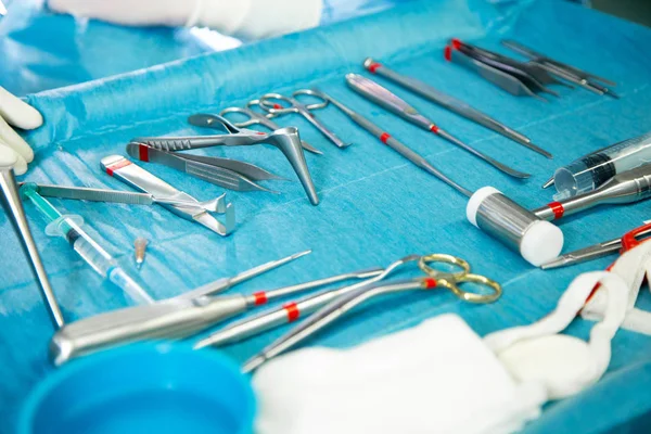 Primer plano de las manos del médico durante la cirugía en el quirófano. Instrumentos de cirugía estéril utilizados en una operación real. El foco está en la fila de asas de abrazadera . — Foto de Stock