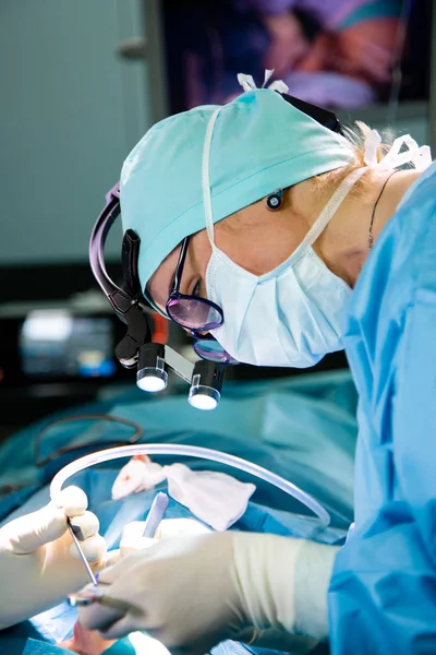 Surgeon and his assistant performing cosmetic surgery on nose in hospital operating room. Nose reshaping, augmentation. Rhinoplasty.