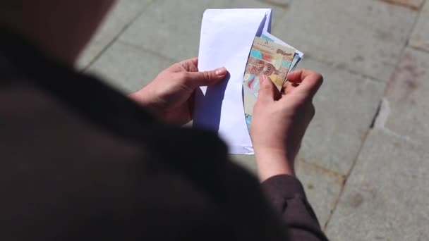 Ein junger Mann kontrolliert das Geld, das sich im Umschlag befindet. Er zählt es. — Stockvideo