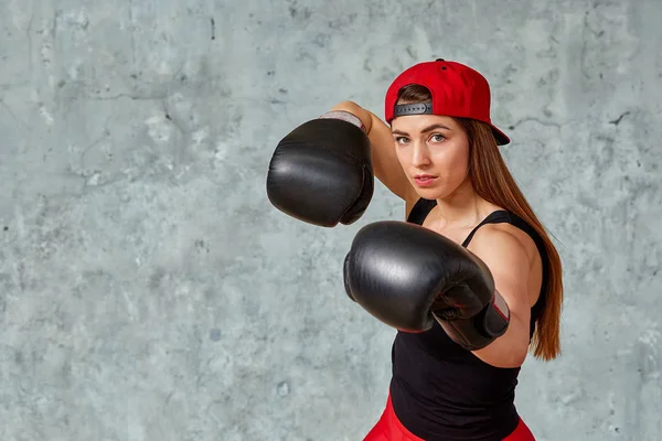 Beautiful athletic girl posing in pink boxing gloves on a gray background. Copy space, close-up. Concept sport, fight, goal achievement.