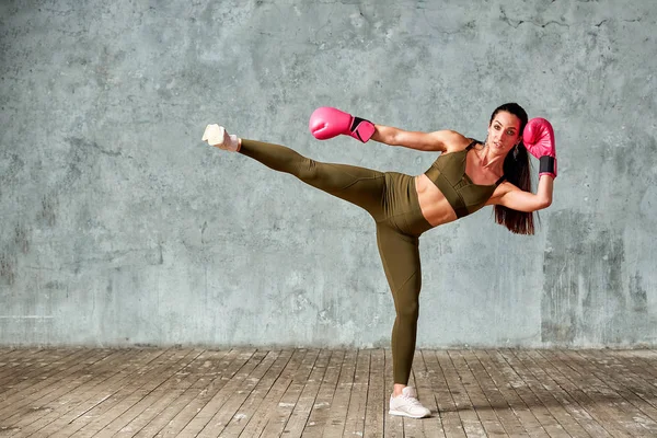 Menina atlética bonita posando em luvas de boxe rosa em um fundo cinza. Espaço para cópia. Conceito esporte, luta, meta de realização . — Fotografia de Stock