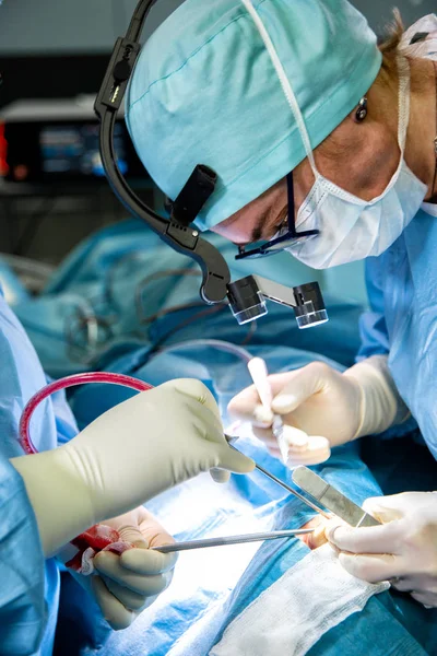 Cirujano realizando cirugía en quirófano del hospital. Cirujano en máscara con lupas durante la procadure médica . — Foto de Stock