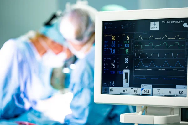 Elektrocardiogram in ziekenhuis chirurgie opererende spoedeisende hulp toont patiënt hartslag met wazig team van chirurgen achtergrond — Stockfoto