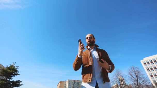 Giovane uomo nervoso emotivamente parlando al telefono. Ragazzo con barba e occhiali parla nervosamente al telefono — Video Stock