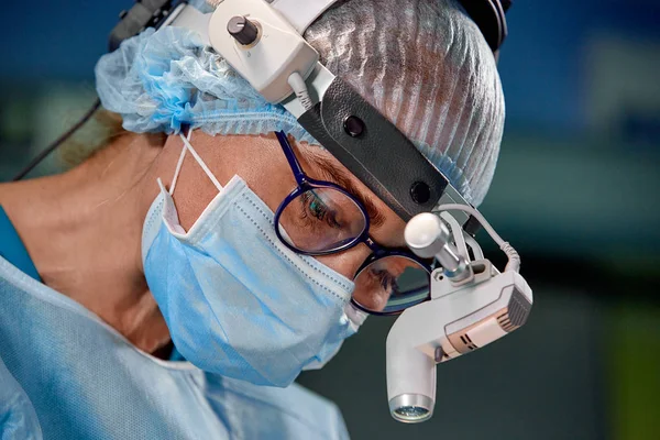 Närbild porträtt av kvinnliga kirurgen läkare bär skyddande mask och hatt under operationen. Sjukvård, medicinsk utbildning, kirurgi koncept. — Stockfoto