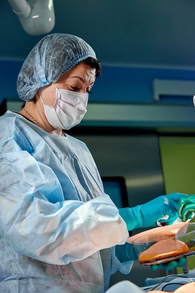 Médico sosteniendo implantes de silicona para aumento de senos en quirófano, primer plano. Cirugía estética — Foto de Stock