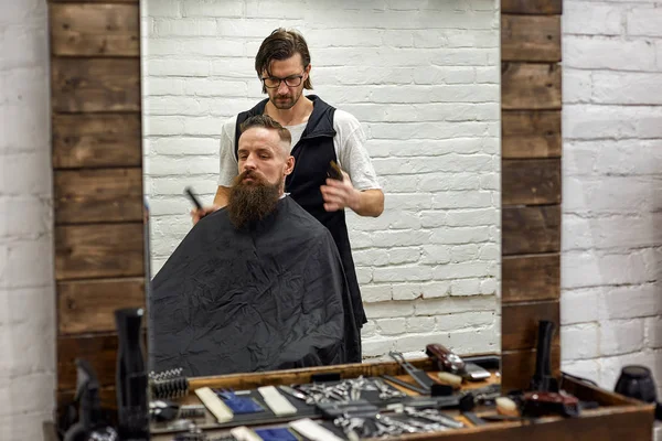 Master taglia capelli e barba di uomini nel barbiere, parrucchiere fa acconciatura per un giovane — Foto Stock