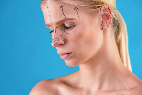 Красавчик нарисовал исправительные линии на женском лице. Перед операцией пластической хирургии. Isolated on blue — стоковое фото