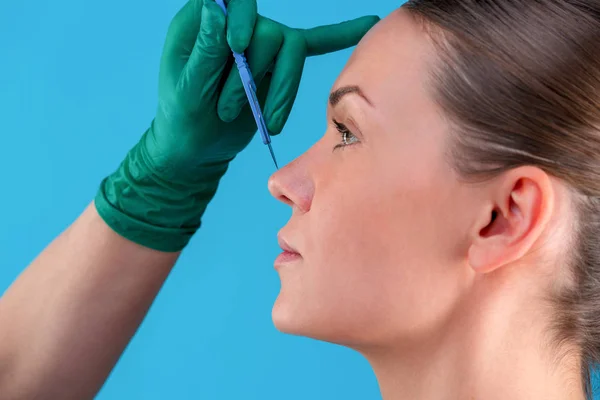 Schoonheidsspecialiste trekken correctie lijnen op vrouw gezicht. Voor plastische chirurgie operetion. Geïsoleerd op blauw — Stockfoto