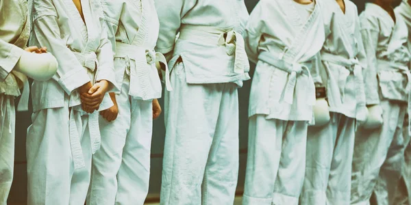 Karate concettuale, arti marziali. Costruzione di studenti nella sala prima della formazione. Kimono, cinture diverse, diversi livelli di allenamento. Da vicino. , — Foto Stock