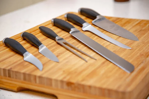 Ensemble de couteaux de cuisine sur une planche à découper en bois — Photo