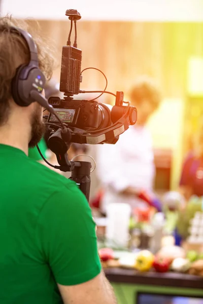 Videógrafo filmando um filme ou um programa de televisão em um estúdio com uma câmera profissional, nos bastidores — Fotografia de Stock