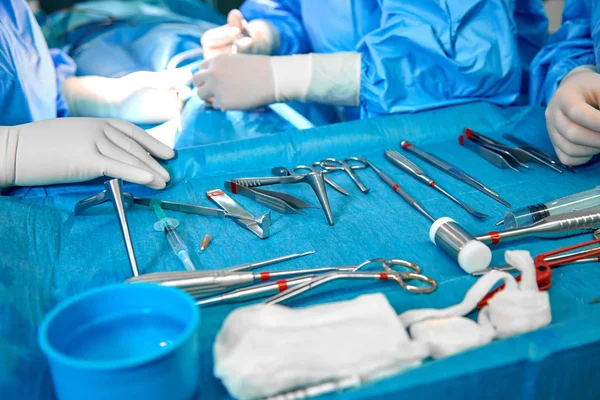 Nahaufnahme der Arzthände während der Operation im Operationssaal. Sterile Operationsinstrumente, die bei einer echten Operation verwendet werden. Schwerpunkt liegt auf der Reihe der Klemmgriffe. — Stockfoto