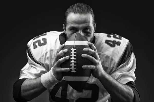 Conceito desportivo. Jogador de futebol americano em preto com bola. Conceito desportivo. close-up, imagem branca preta . — Fotografia de Stock
