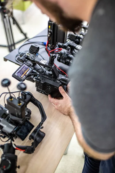 Videofilmer, der einen Film oder eine Fernsehsendung in einem Studio mit einer professionellen Kamera hinter der Bühne aufnimmt — Stockfoto