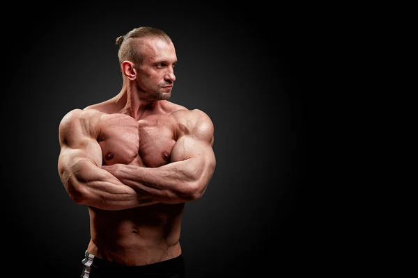 Sport concept. Fitness atleet met perfecte spieren poses op camera over zwarte achtergrond. — Stockfoto
