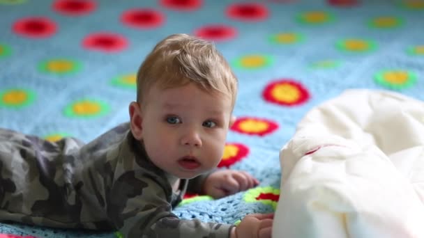 Boldog baba feküdt az ágyon a gyomrában, és játszik egy párnát. A koncepció az első mozgalom a gyerekek — Stock videók