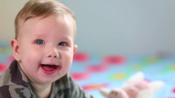 Beautiful Smiling Baby: Ένα πανέμορφο μωράκι ξαπλώνει στο κρεβάτι και χαμογελά στην κάμερα με ένα ωραίο μαλακό φόντο εστίασης — Αρχείο Βίντεο