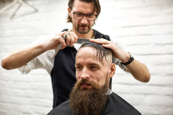 Meister schneidet Männern Haare und Bart im Friseursalon, Friseur frisiert jungen Mann — Stockfoto