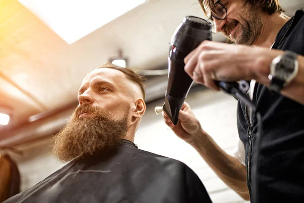 Meister schneidet Männern Haare und Bart im Friseursalon, Friseur frisiert jungen Mann — Stockfoto