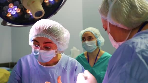 N the hospital operating room. A diverse team of professional surgeons and nurses, a suture wound after a successful operation — Stock Video