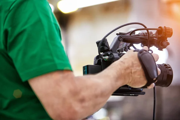 Videografo che gira un film o un programma televisivo in uno studio con una macchina fotografica professionale, dietro le quinte — Foto Stock