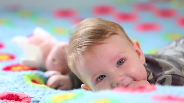 Beautiful Smiling Baby: Ein wunderschönes kleines Baby liegt auf dem Bett und lächelt in die Kamera mit einem schönen weichen Fokushintergrund — Stockvideo