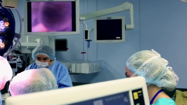 Professionella kirurger och assistenter Talk och används dator under kirurgi. De arbetar i det moderna sjukhuset Operations salen. — Stockvideo