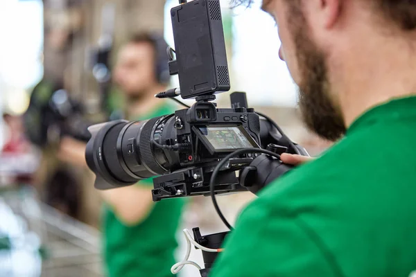 Videógrafo filmando um filme ou um programa de televisão em um estúdio com uma câmera profissional, nos bastidores — Fotografia de Stock