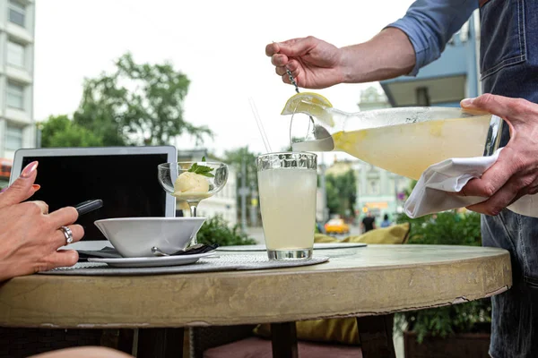 Офіціант наповнює воду лимоном і м'ятою в окуляри на сервірувальному столі . — стокове фото