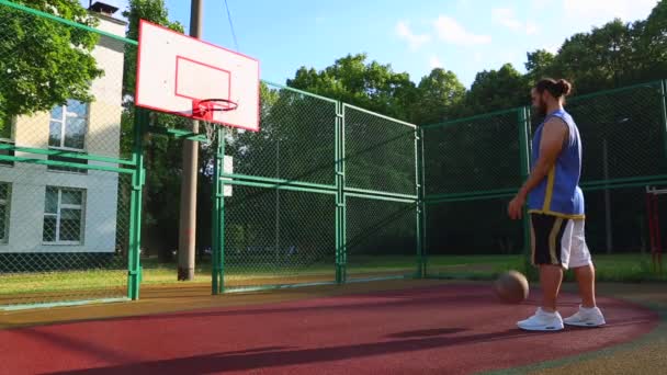 Basketbalspeler traint op straat om de bal in de mand te scoren. Trainings spel van basketbal. Concept sport, motivatie, doel verwezenlijking, gezonde levensstijl. — Stockvideo