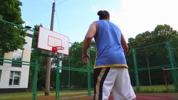 Basketbalspeler traint op straat om de bal in de mand te scoren. Trainings spel van basketbal. Concept sport, motivatie, doel verwezenlijking, gezonde levensstijl. — Stockvideo