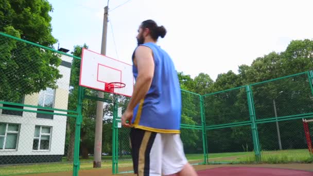 Basketbalspeler traint op straat om de bal in de mand te scoren. Trainings spel van basketbal. Concept sport, motivatie, doel verwezenlijking, gezonde levensstijl. — Stockvideo