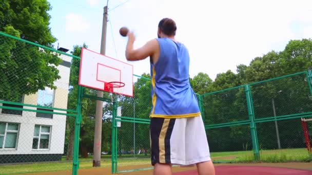 Basketbalspeler traint op straat om de bal in de mand te scoren. Trainings spel van basketbal. Concept sport, motivatie, doel verwezenlijking, gezonde levensstijl. — Stockvideo