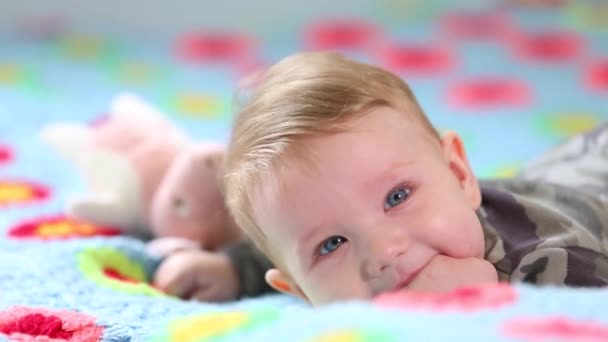 Mooie glimlach Baby: Een prachtige kleine baby ligt op het bed en glimlacht naar de camera met een mooie zachte focus achtergrond — Stockvideo