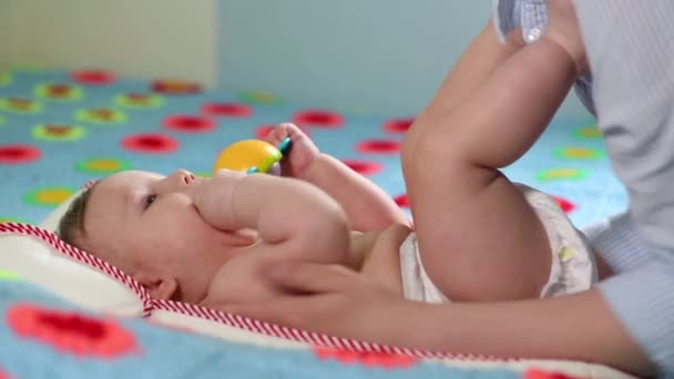 Los mejores momentos de la vida, una amorosa madre joven y feliz abraza a un hijo lactante, sobre una manta azul con flores, sobre un fondo blanco. concepto de amor, familia y felicidad Concepto: niños, niños, bebés — Vídeo de stock