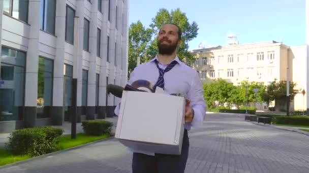 Concepto de despido del trabajo, contratación. Un empleado camina entre edificios de oficinas con una caja de cartón y documentos con una flor de escritorio. Perdí mi trabajo debido a un error . — Vídeos de Stock