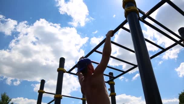 Concetto motivazioni sportive. Vista posteriore di un uomo muscoloso tirato su una barra orizzontale all'aperto in una giornata di sole. Allenamento atletico all'aperto, crossfit . — Video Stock