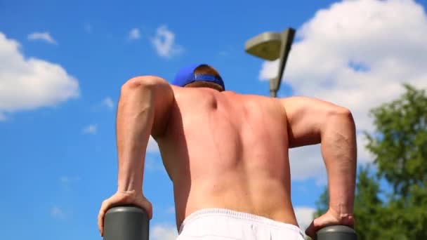 Sport motivations. Muscular athlete wrung out on uneven bars outdoors on a sunny day. Healthy lifestyle, body development, beauty, crossfit. — Stock Video
