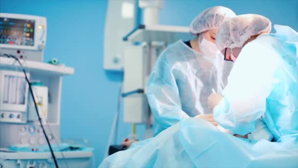 Professional surgeons and assistants discuss the operation during it. They work in a modern hospital operating room. Medical concept, surgery, plastic surgery, beauty, health. — Stock Video