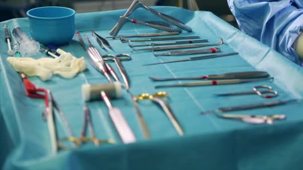 Medicina conceptual, cirugía. Mesa de operaciones con una herramienta para cirugía, primer plano, luz azul. En la mesa se extienden los instrumentos esterilizados de cirujanos, bisturíes, clips, tampones, jeringas . — Vídeo de stock